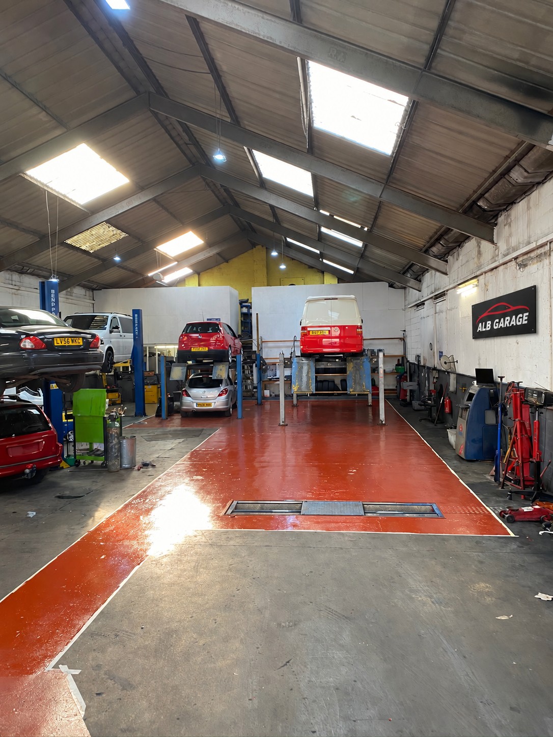 Inside ALB Garage, with vehicle lifts and the ALB Garage sign on the right wall